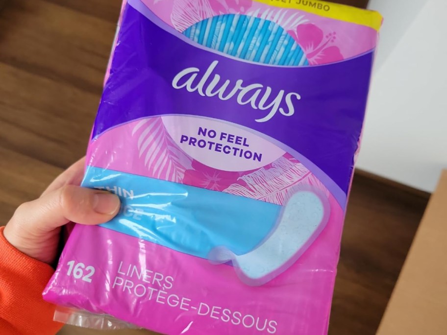 A hand holding up a package of Always panty liners.