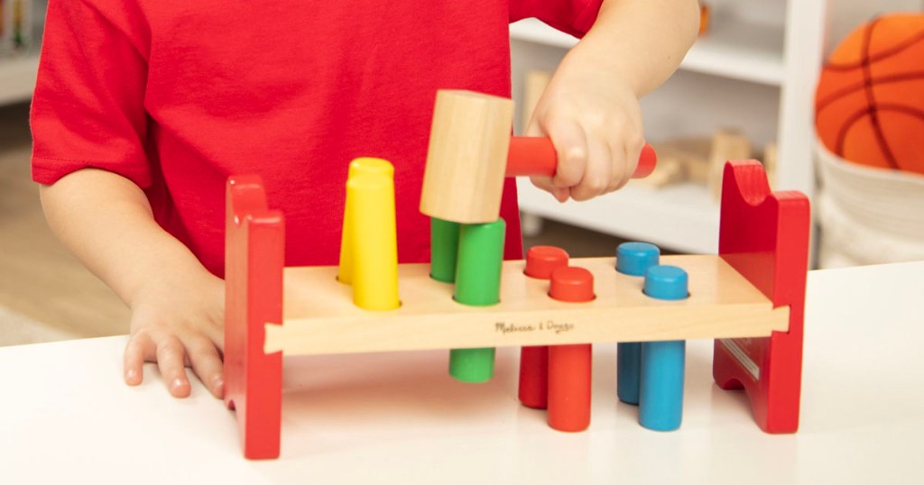 kid playing with a melissa and doug toy hammer set