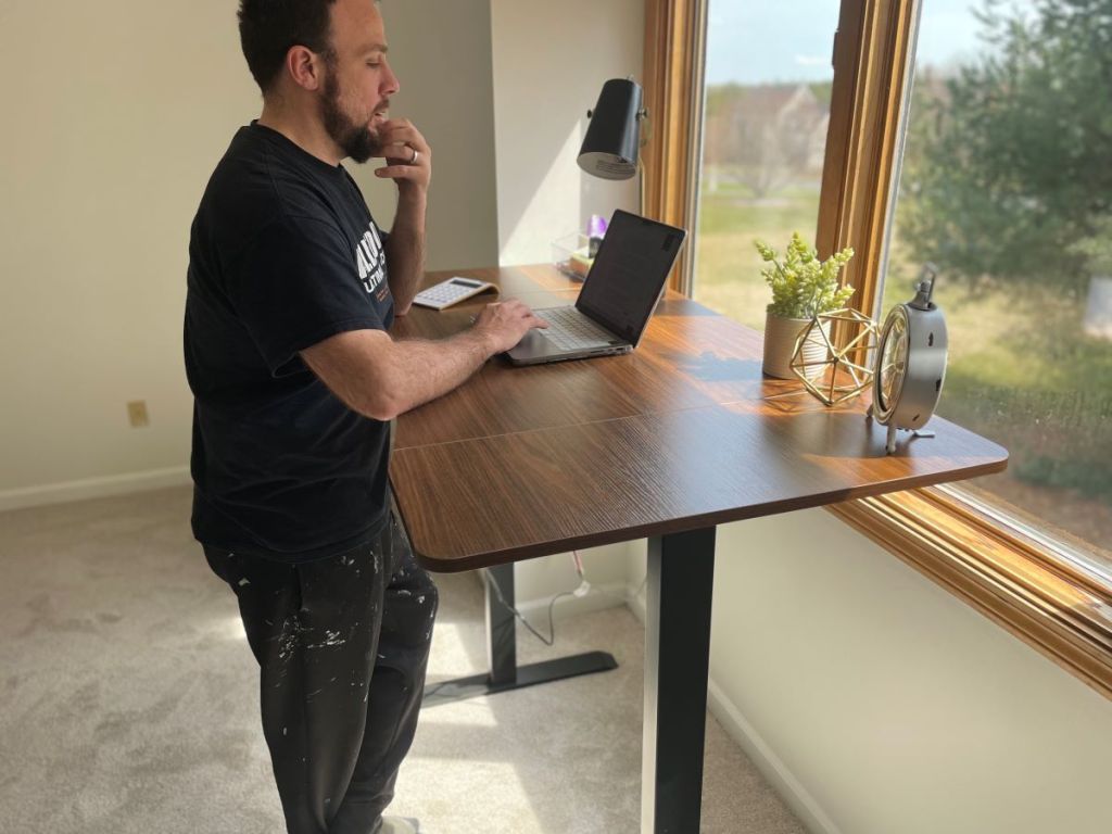 Man standing next to an electric standing desk