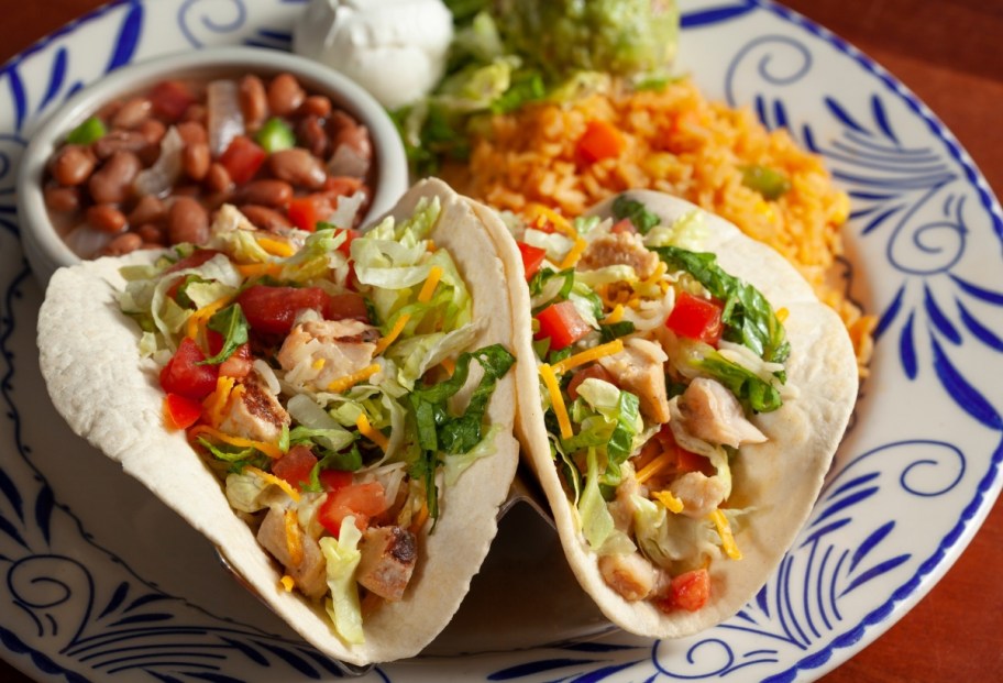 two chicken tacos & sides on a white and blue plate