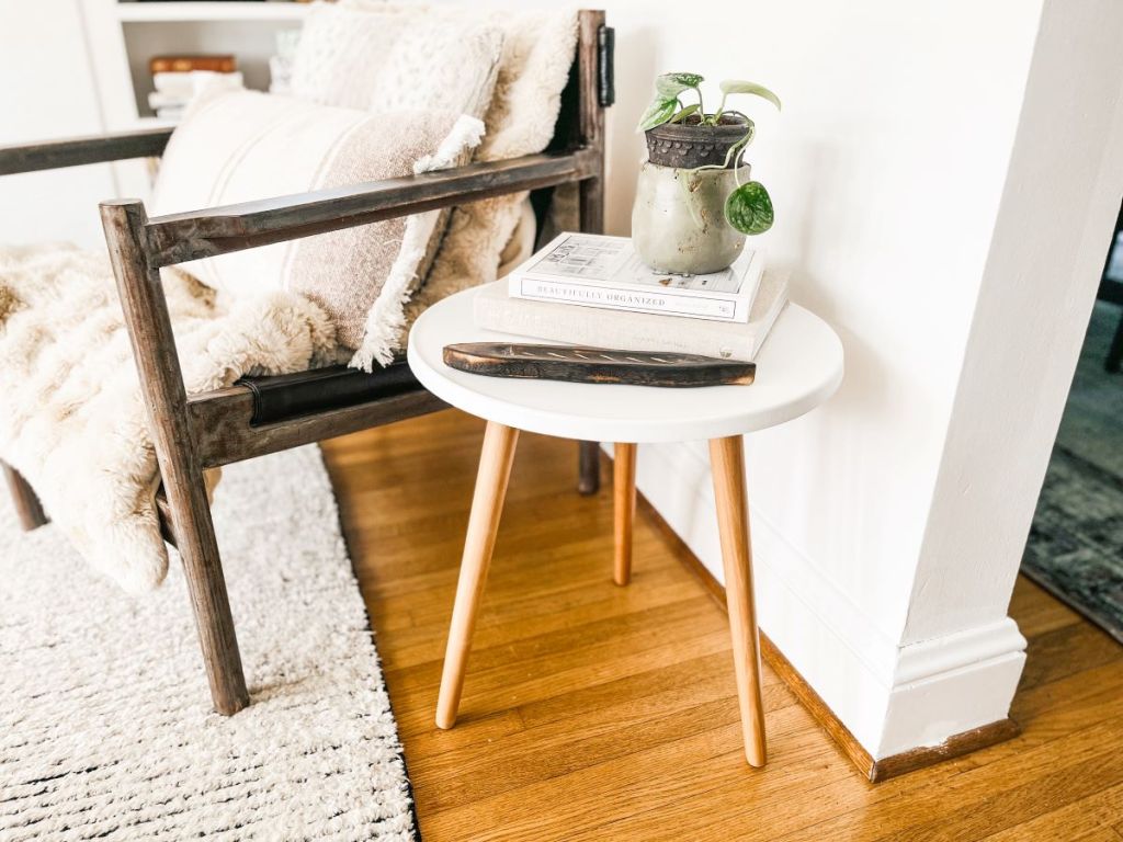 Side table with a plant and books on it next to a chair