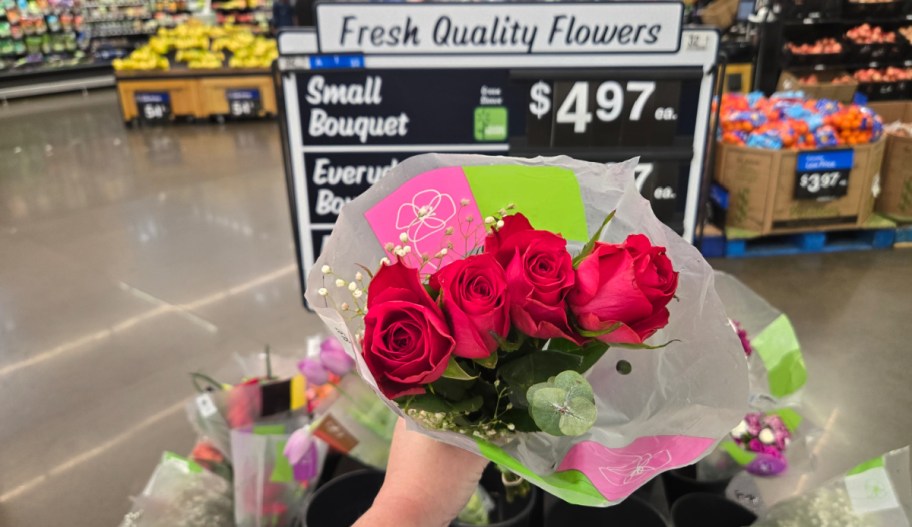 hand holding a bouquet of flower in front of a walmart sign