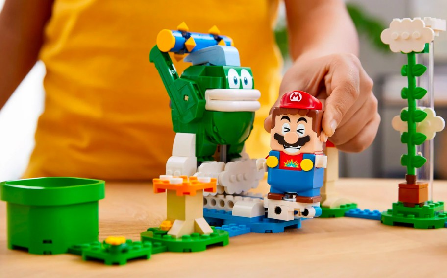 A child holding Mario playing with a LEGO Super Mario Big Spike&rsquo;s Cloudtop Challenge set