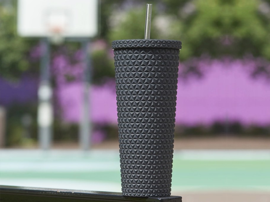 matte black tumbler outside with basketball court in background