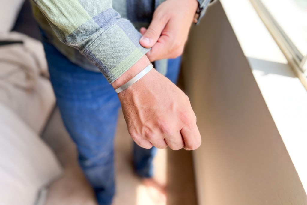 man grabbing shirt sleeve with silver bracelet