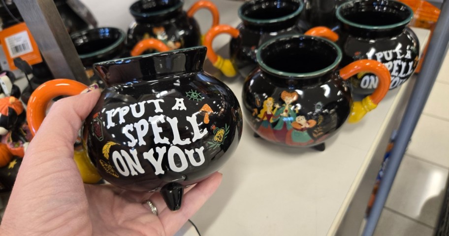 hand holding a Hocus Pocus cauldron mug, with more behind it showing the front and back
