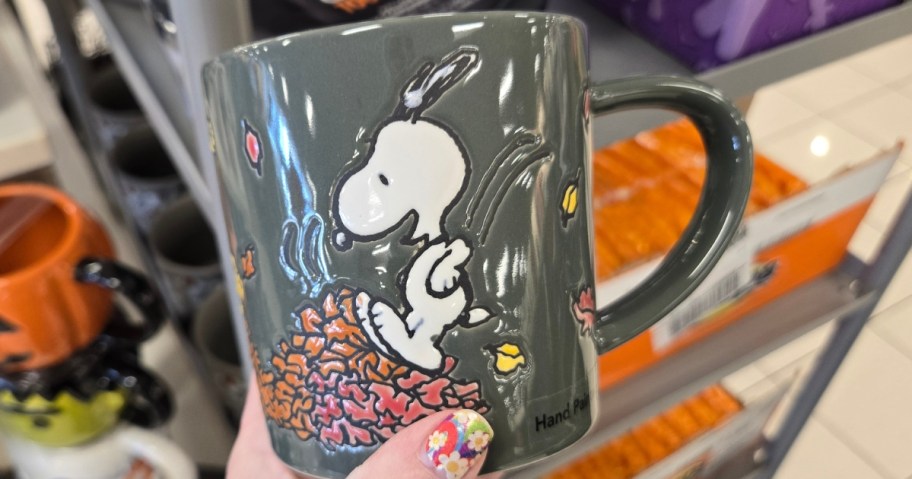 hand holding a Snoopy fall themed coffee mug