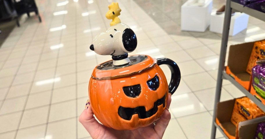 hand holding a lidded jackolantern coffee mug with Snoopy & Woodstock on top