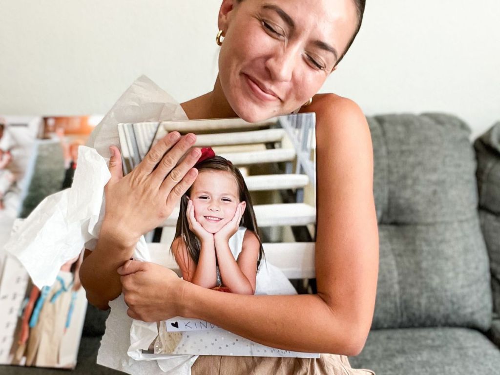 woman holding a canvas print that features a young girl