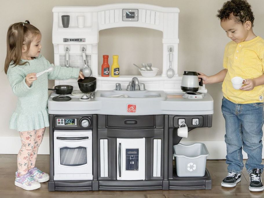 two children playing with a large kitchen 