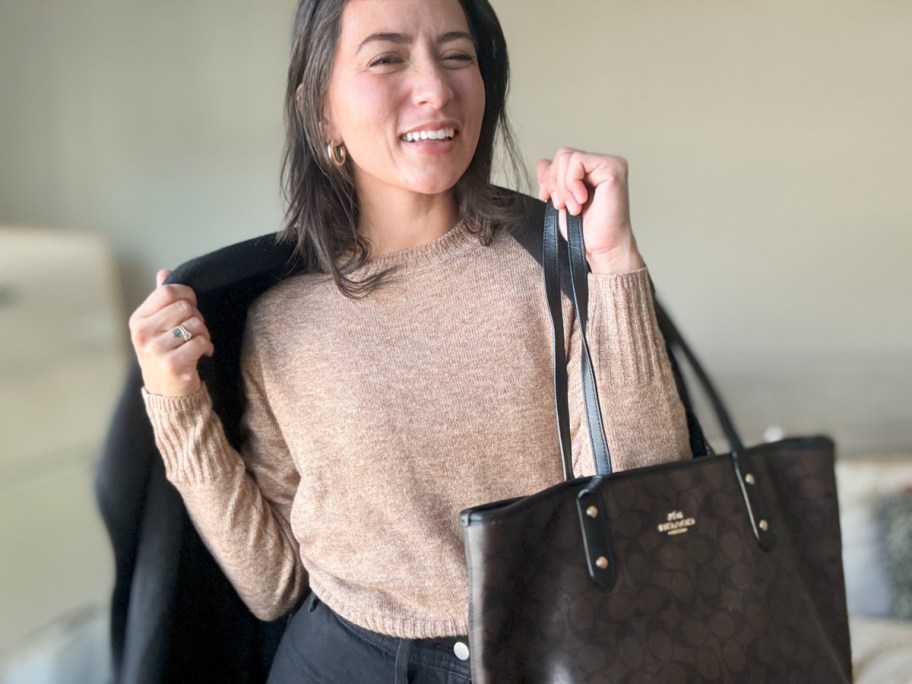woman holding purse wearing tan sweater