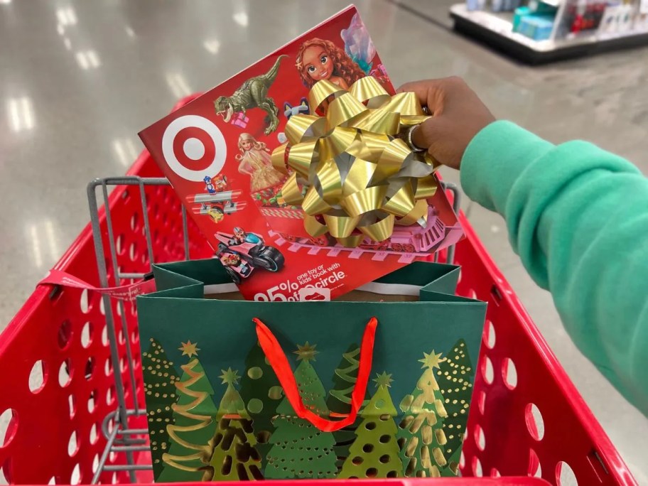 adding a Target toy book to a gift bag in a red shopping cart
