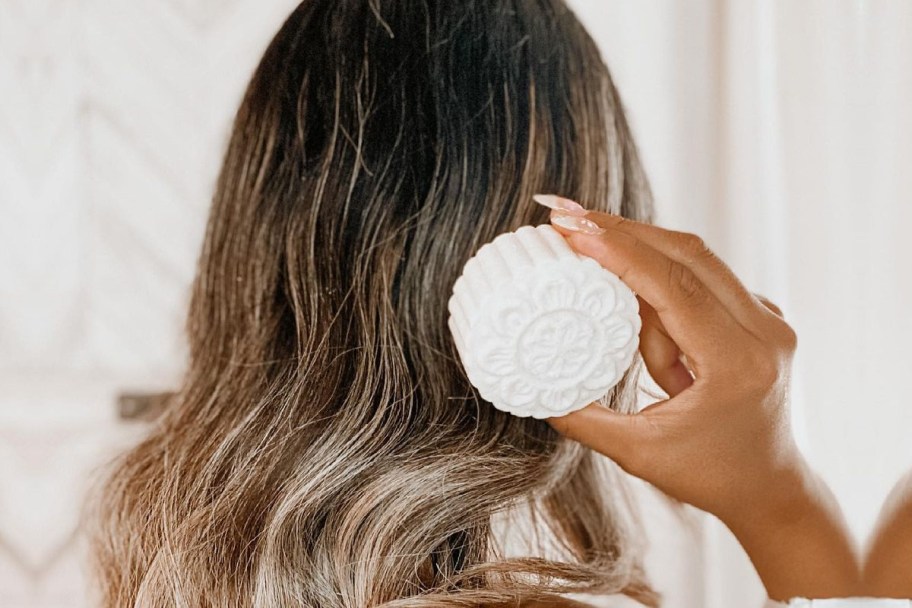 woman holding shampoo bar to hair