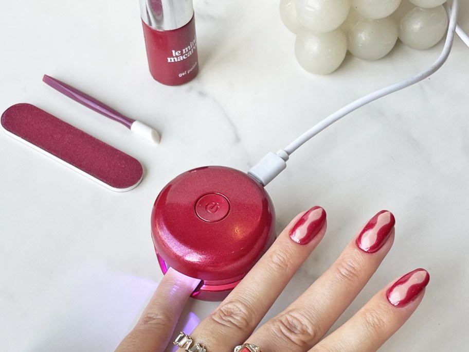 woman doing an at-home gel manicure with mini led light