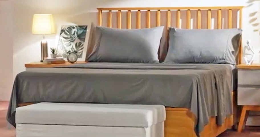 grey sheet set on a bed with a wooden headboard