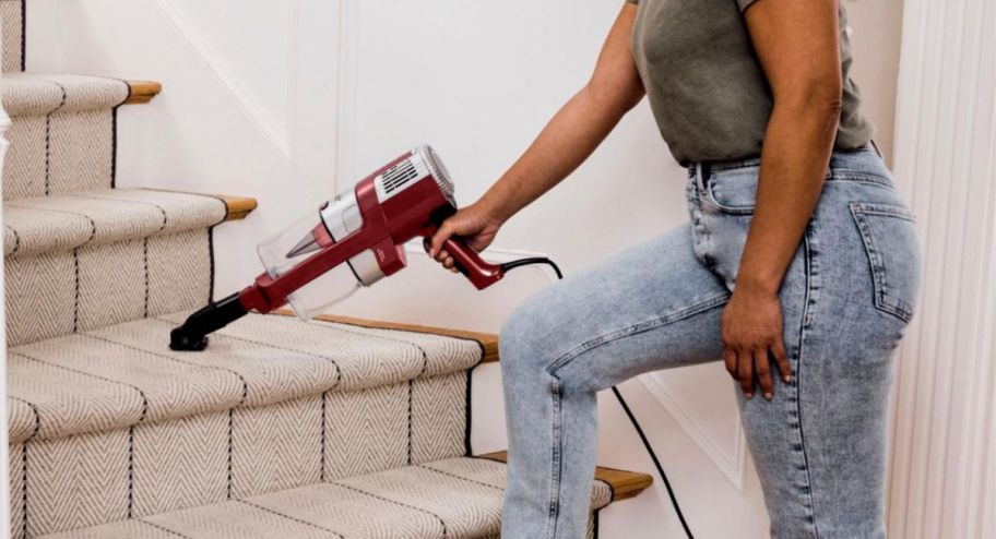 woman using shark vacuum to go up the stairs
