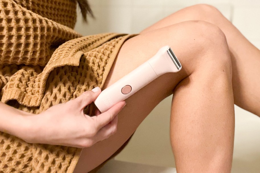 woman holding an electric razor against leg