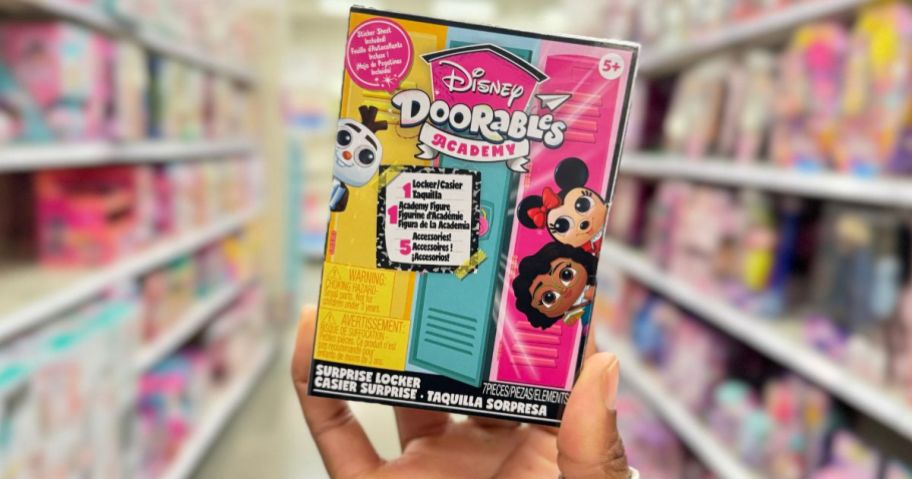 a womans hand holding a box of disney doorable figures
