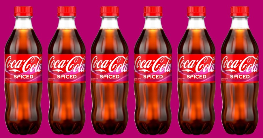 6 bottles of Coca-Cola Spiced soda on a purple background