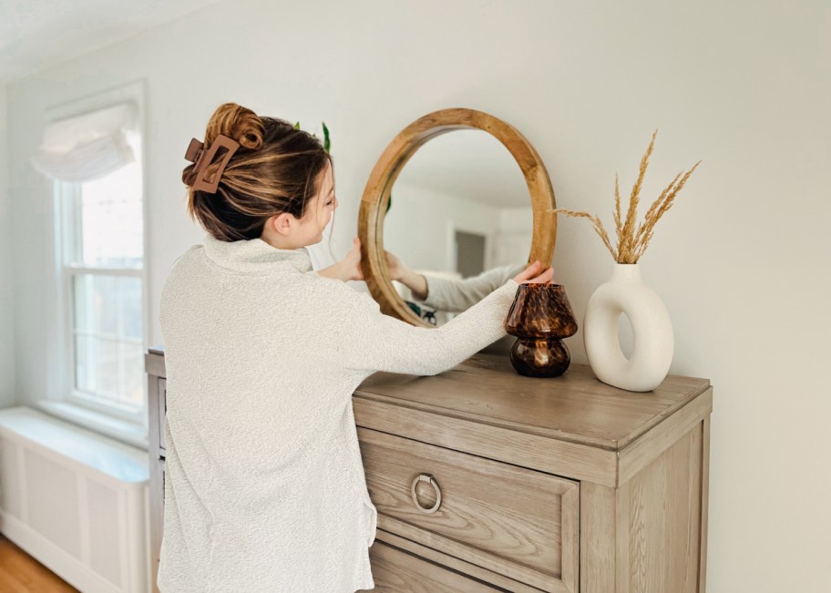 Woman placing a Walmart mirror atop her dresser