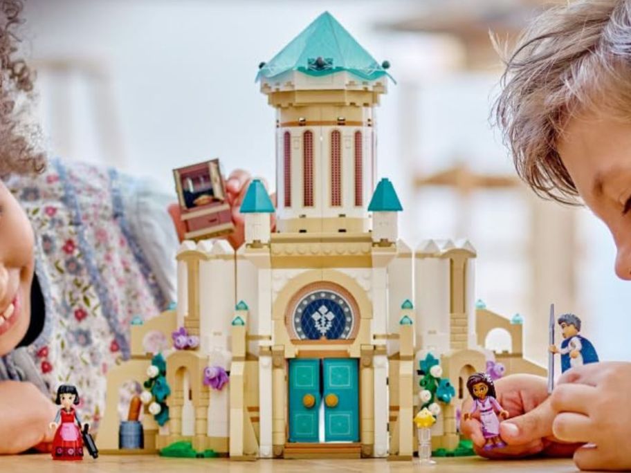 Two kids playing with a LEGO Disney Wish King Magnifico&rsquo;s Castle