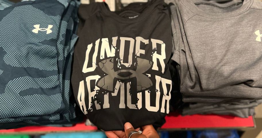 hand touching a folded under armour t-shirt
