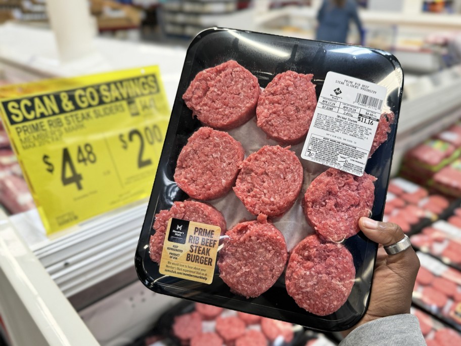 hand holding up a pack of Member's Mark Prime Rib Ground Beef Sliders with yellow scan & go sale sign in background