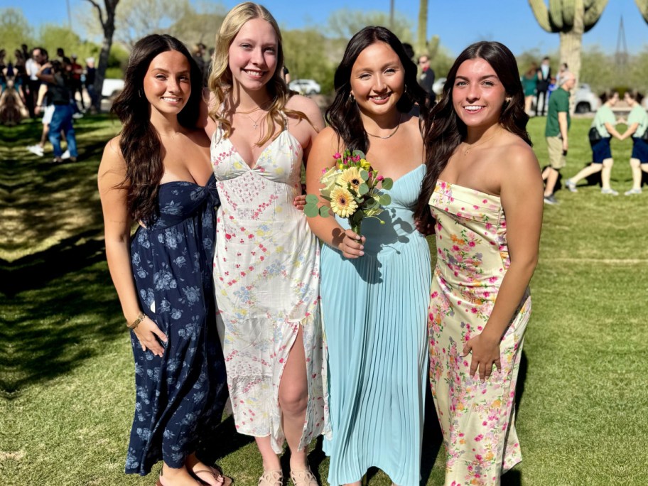 four girls in prom dresses standing outside