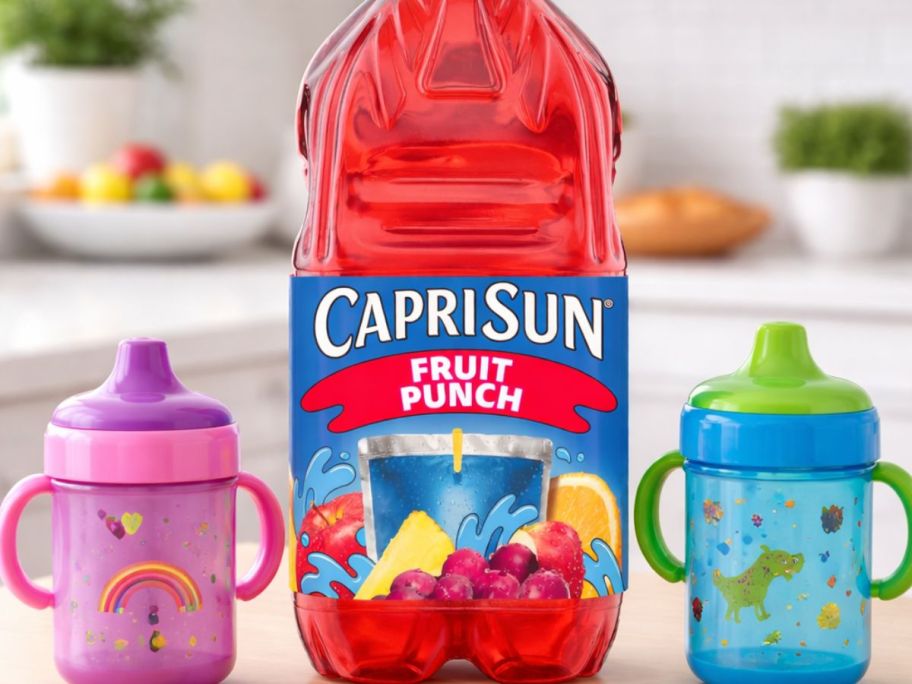 Caprisun fruit punch bottle in the middle of a kitchen table with sippy cups next to it 