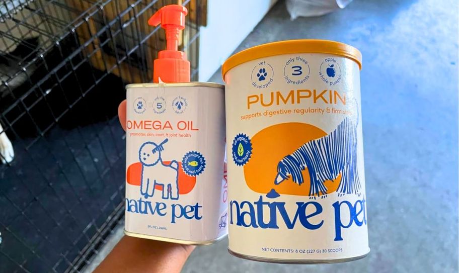 a hand holding a can of native pet fish oil and pumpkin powder