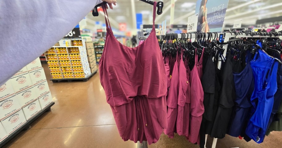 person holding time and tru swim romper on hanging in walmart store