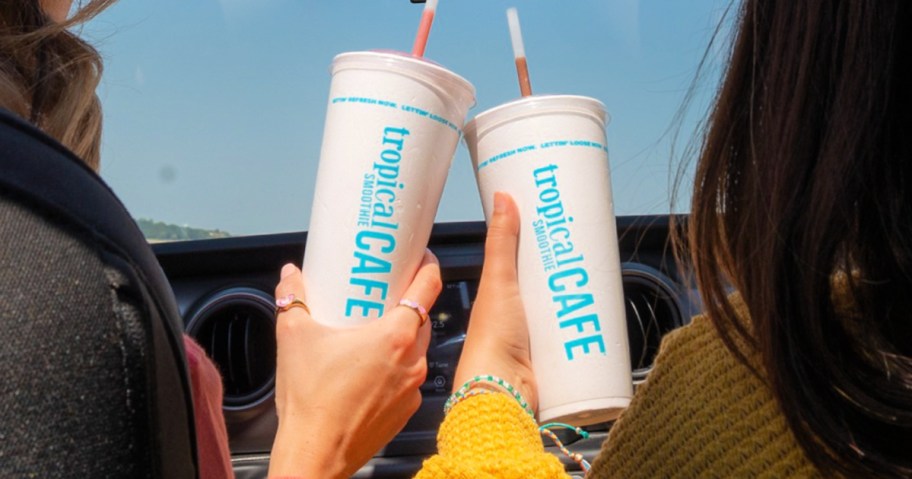 Women holding Styrofoam tropical smoothie caf&eacute; cups inside car