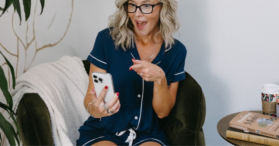 woman holding phone in navy pajama set sitting on chair