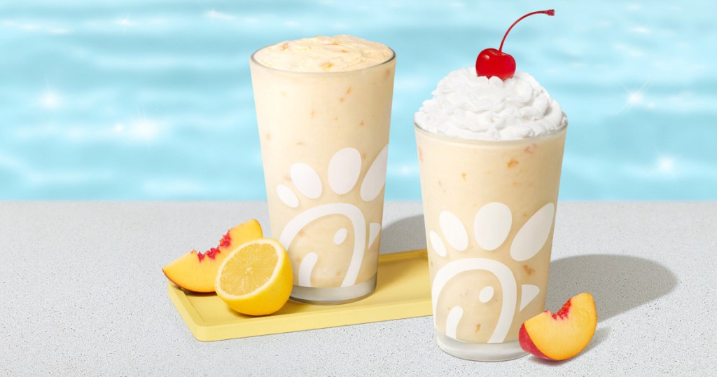 Chick-fil-A peach milkshake, and glass cups next to pool with sliced peaches