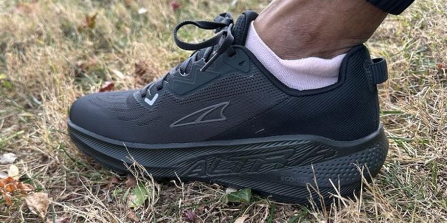 person wearing black altra shoes on grass