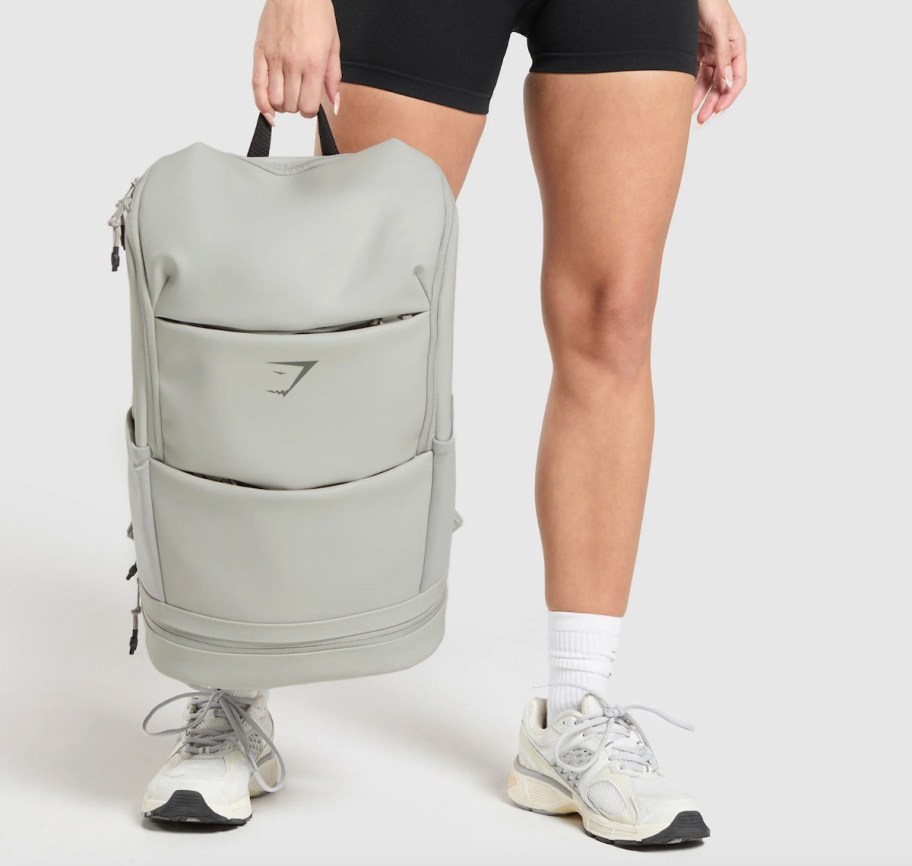 woman holding light gray waterproof backpack