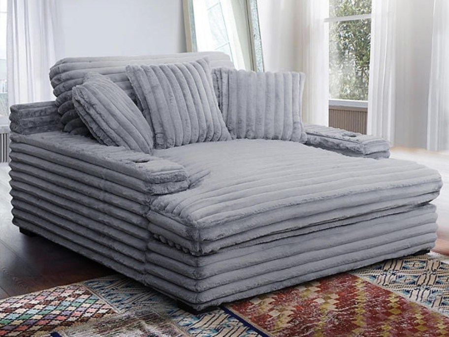 a large grey chaise lounger with pillows in a living room