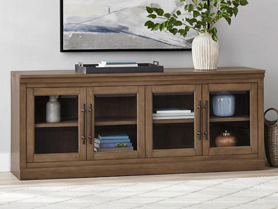 a large wood tv console with glass cabinet doors
