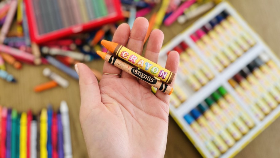 Hand holding two types of yellow crayons