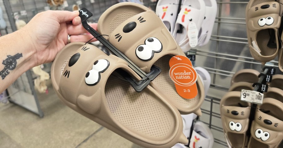 hand holding up a brown pair of dog themed kids sandals in store