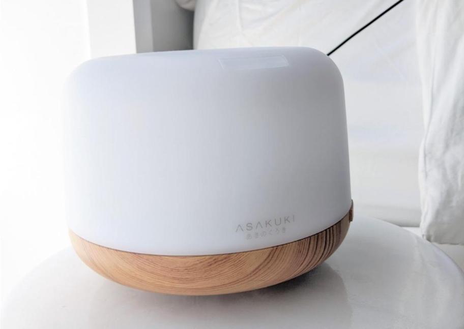 Small wood and white colored essential oils diffuser on nightstand