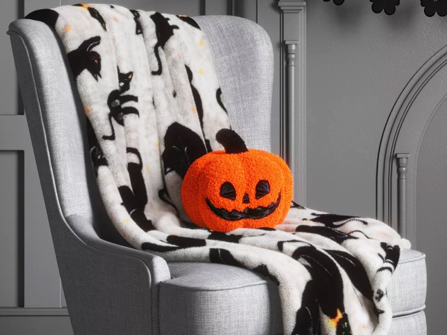 black cat throw blanket on a chair with a pumpkin throw pillow