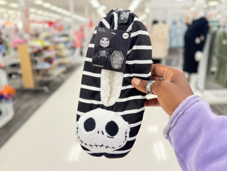 Hand holding up Jack Skellington Halloween slippers from Target