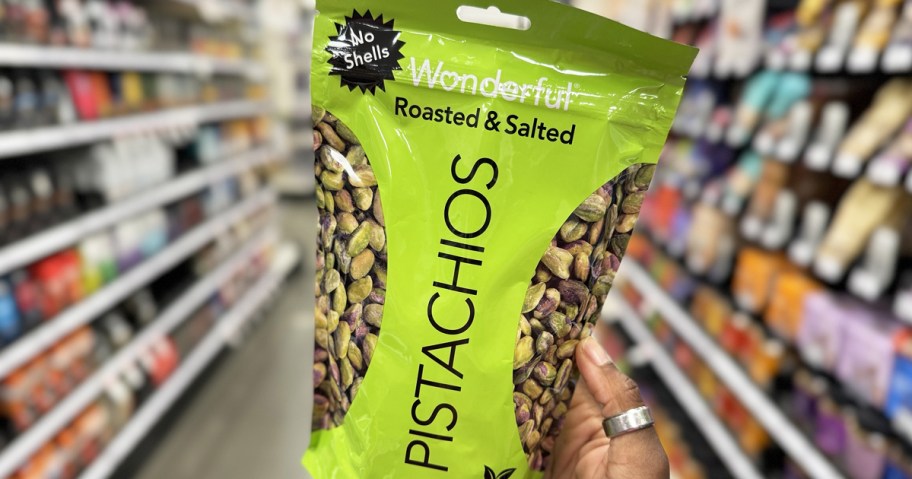 holding up a green bag of Wonderful Pistachios in store