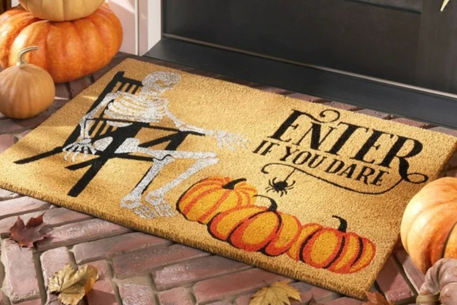 skeleton sitting on chair with pumpkins on coir mat