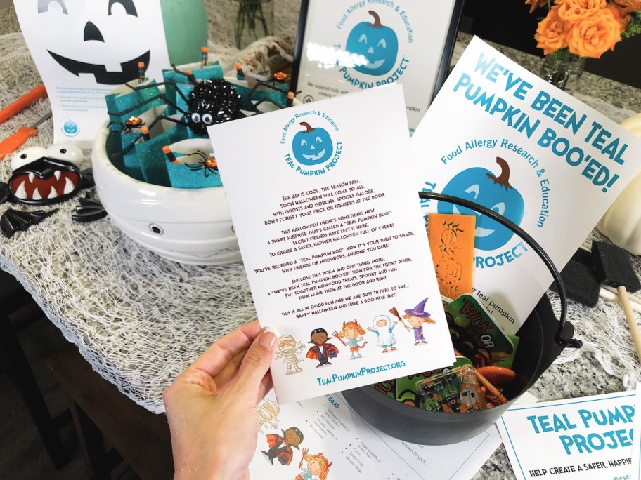 hand holding teal pumpkin project flyer in front of bowls of non candy dishes