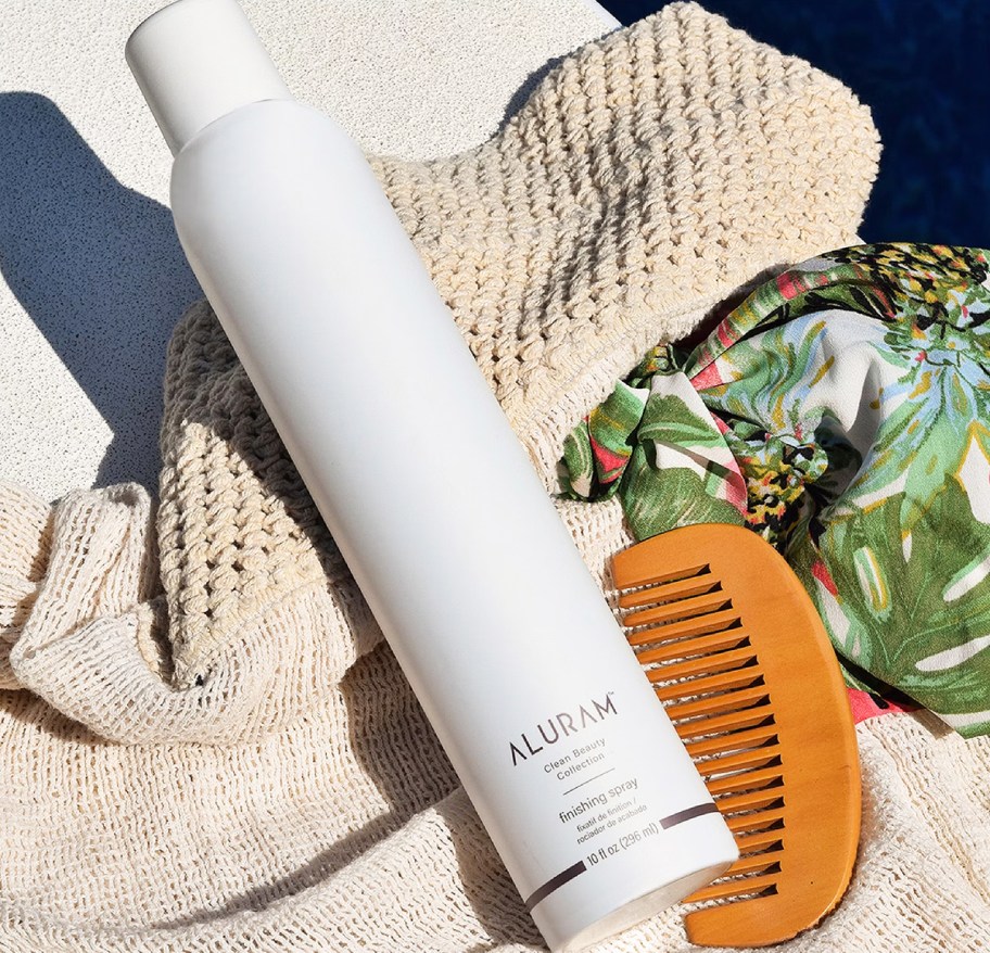 white can of Aluram Finishing Flexible Hold Hair Spray near wood comb