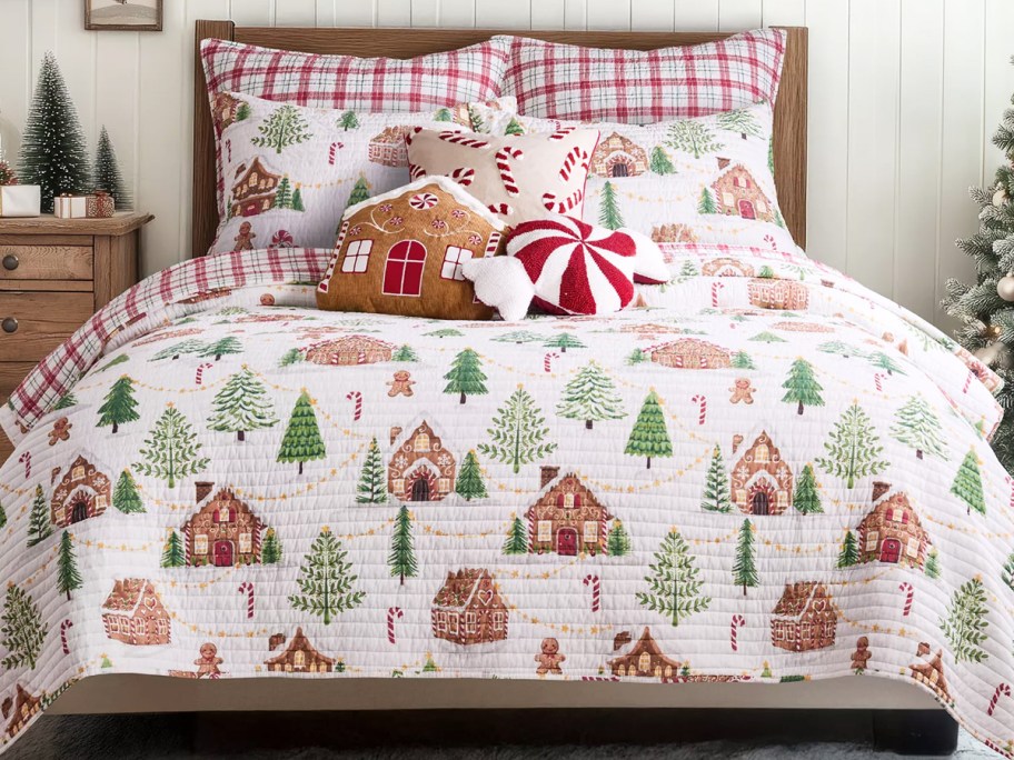 gingerbread cabin print quilt on a bed with christmas throw pillows