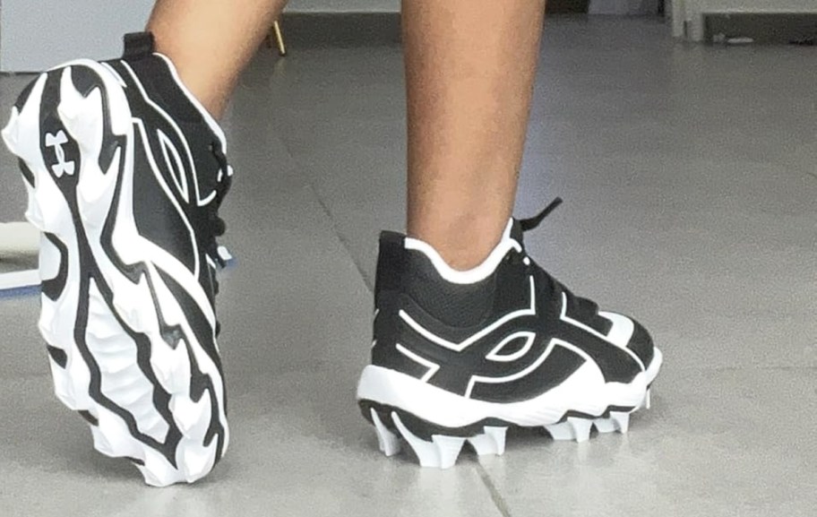 boy wearing a pair of black and white under armour cleats