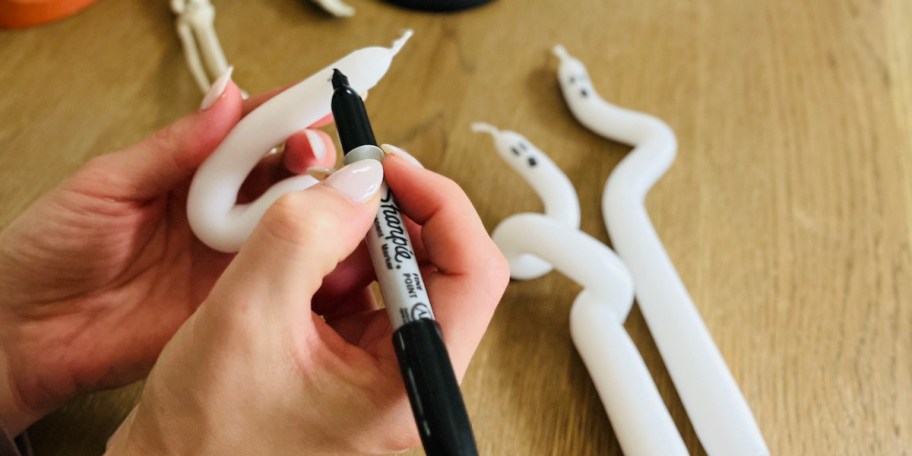 hand drawing ghost face on white taper candle 